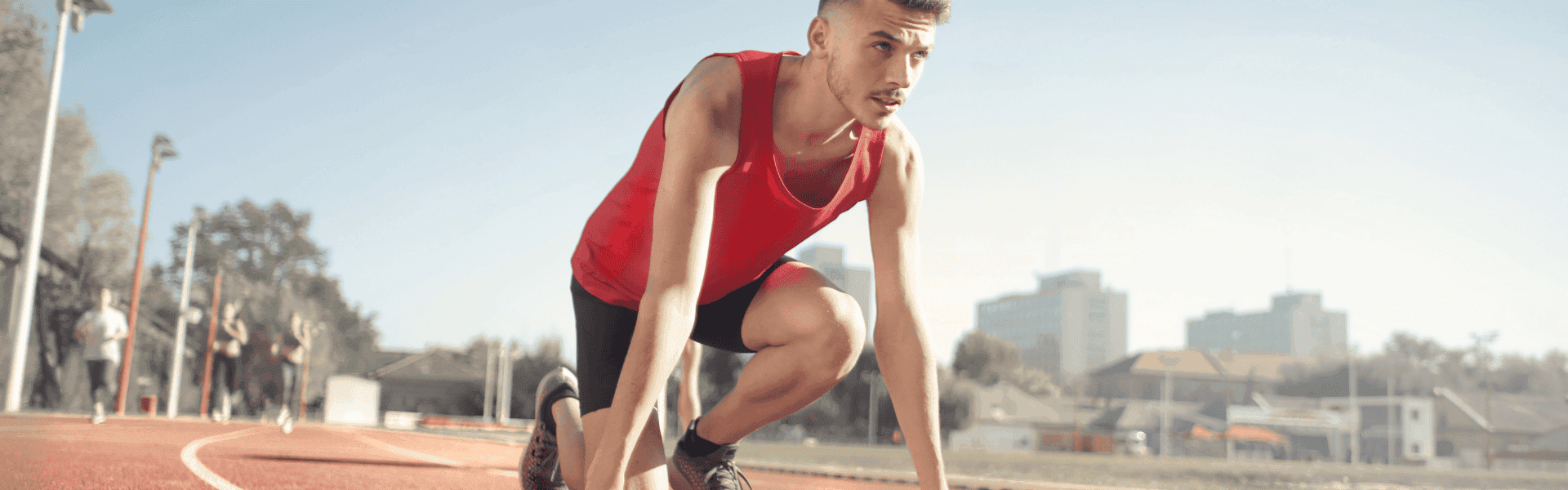 junger sportlicher Mann mit Sport-Shirt trainiert auf einem Rennrad. Die Sonne scheint. 