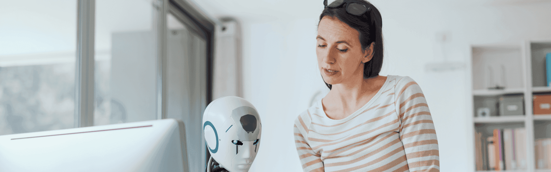 Mitarbeiterin unterhält sich mit einem Roboter am Schreibtisch