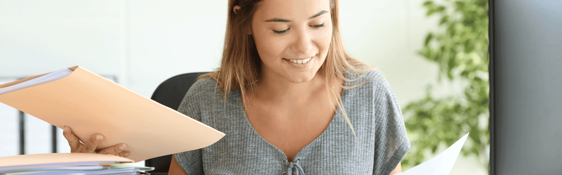 Bürokauffrau blättert in Unterlagen am Schreibtisch