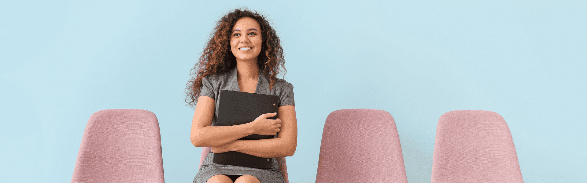 junge Bewerberin wartet sitzend auf einem Stuhl auf ihr Vorstellungsgespräch